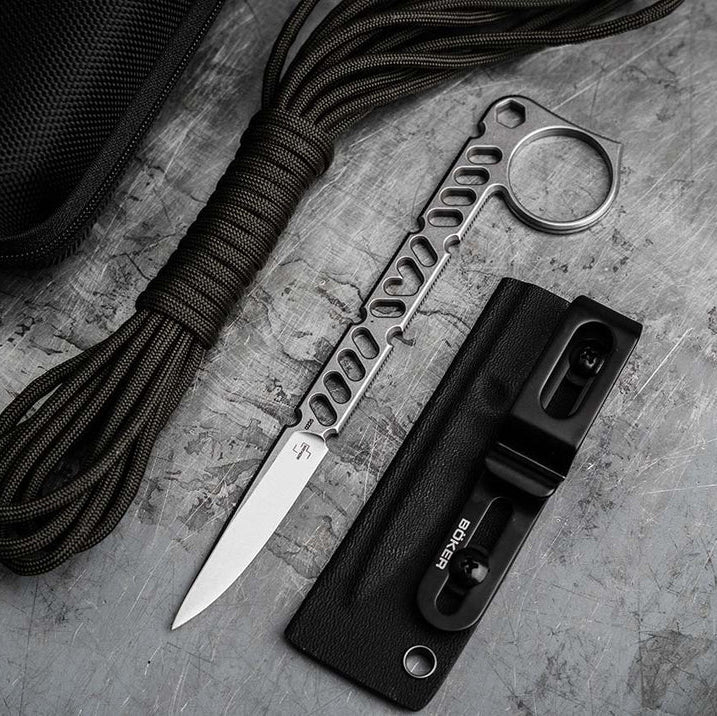 A tactical folding knife Boeker Sigurd 42 with a textured black handle and silver blade, shown alongside a black nylon sheath and a coiled green cord on a gray stone-textured background.