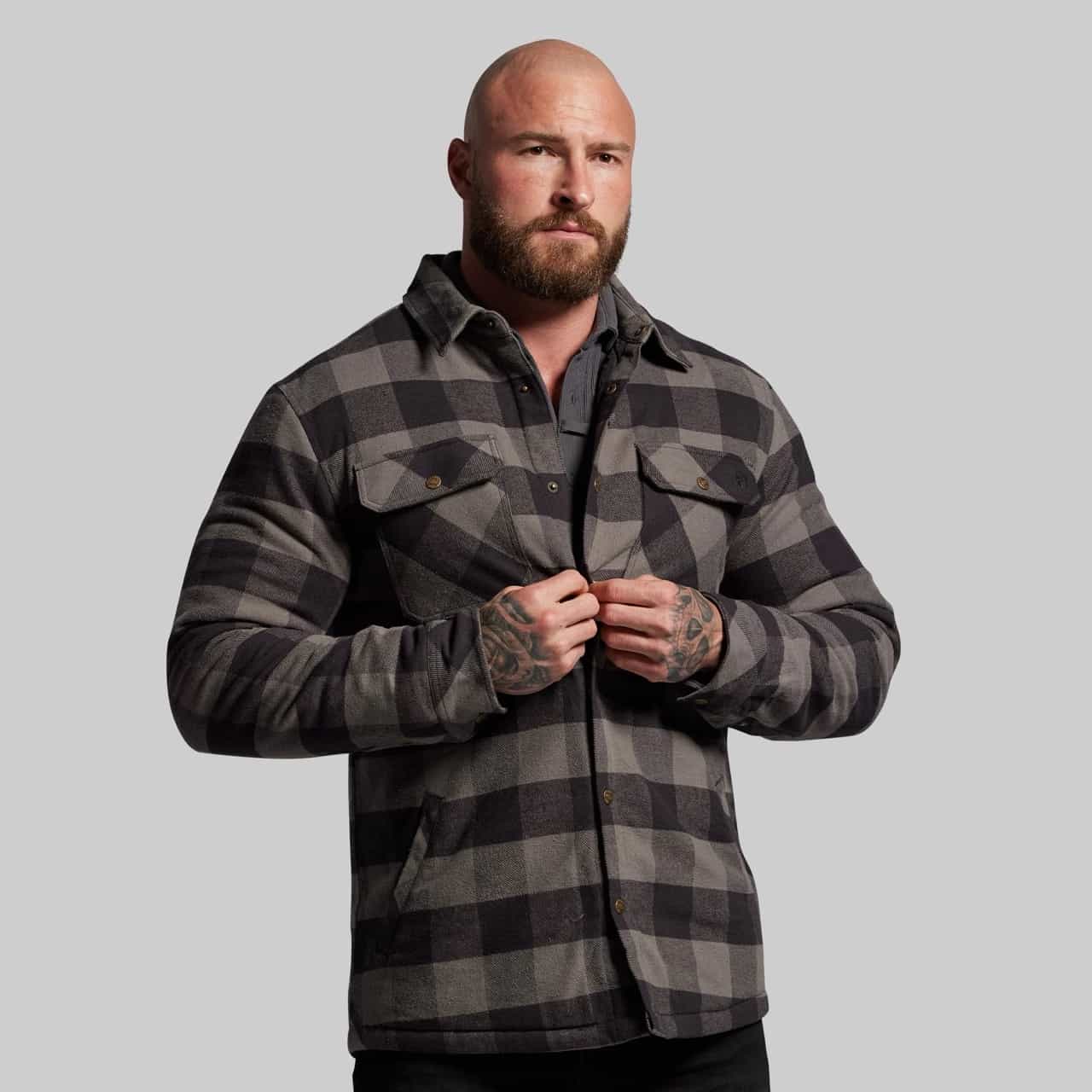 Man wearing a gray and black plaid shirt against a plain background
