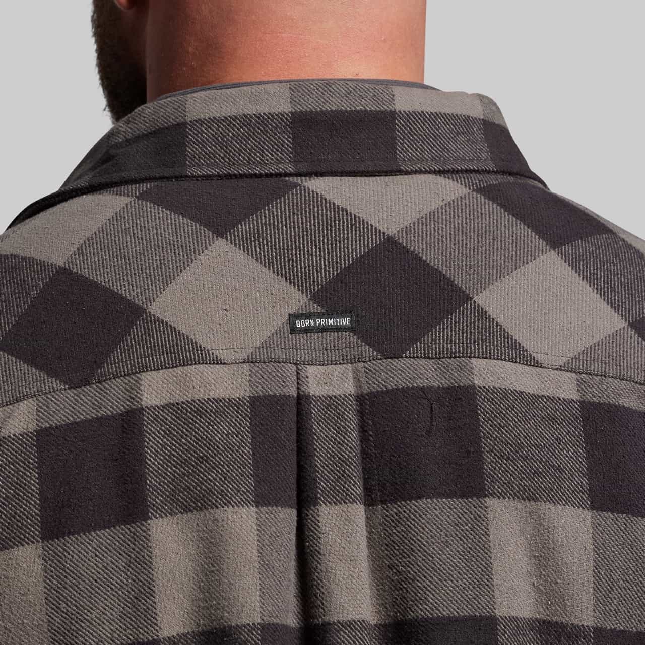Gray and black checkered shirt with a brand logo on the collar against a gray background