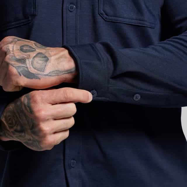 Person wearing a dark blue shirt with tattooed hands