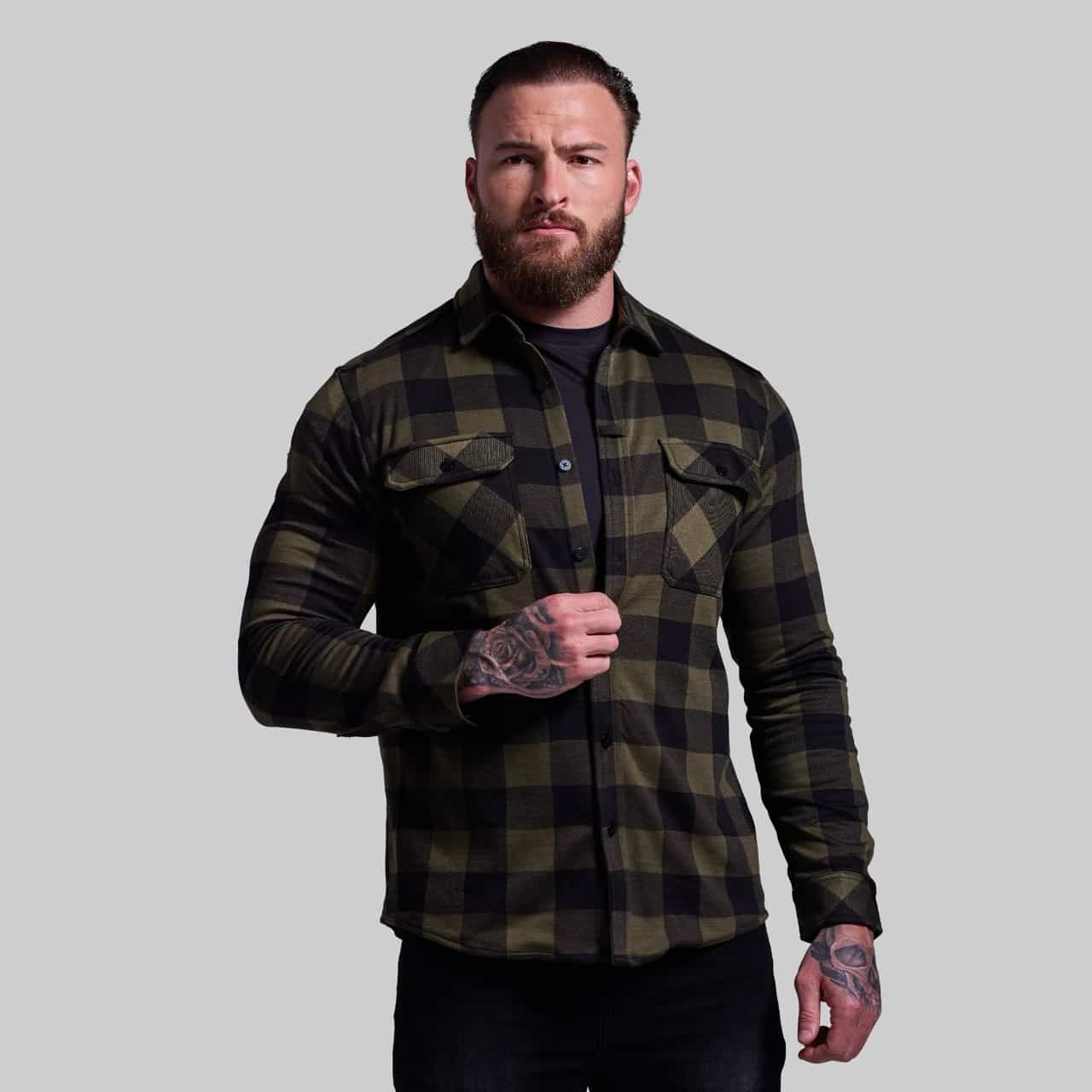 Man wearing a green and black plaid shirt against a gray background