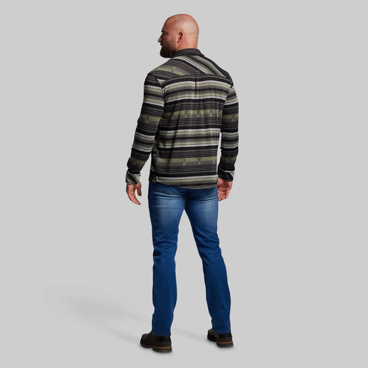 Man wearing a striped sweater and blue jeans on a gray background