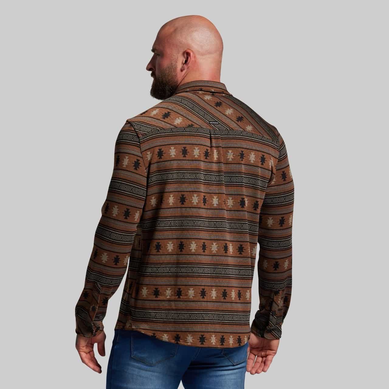 Man wearing a patterned brown shirt against a gray background