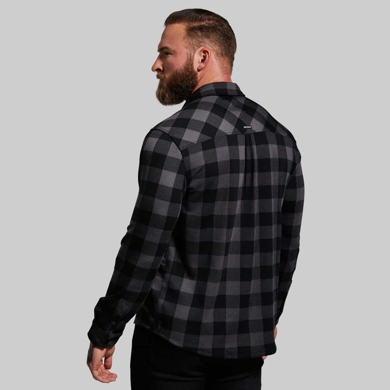 Man wearing a black and gray checkered shirt on a light gray background