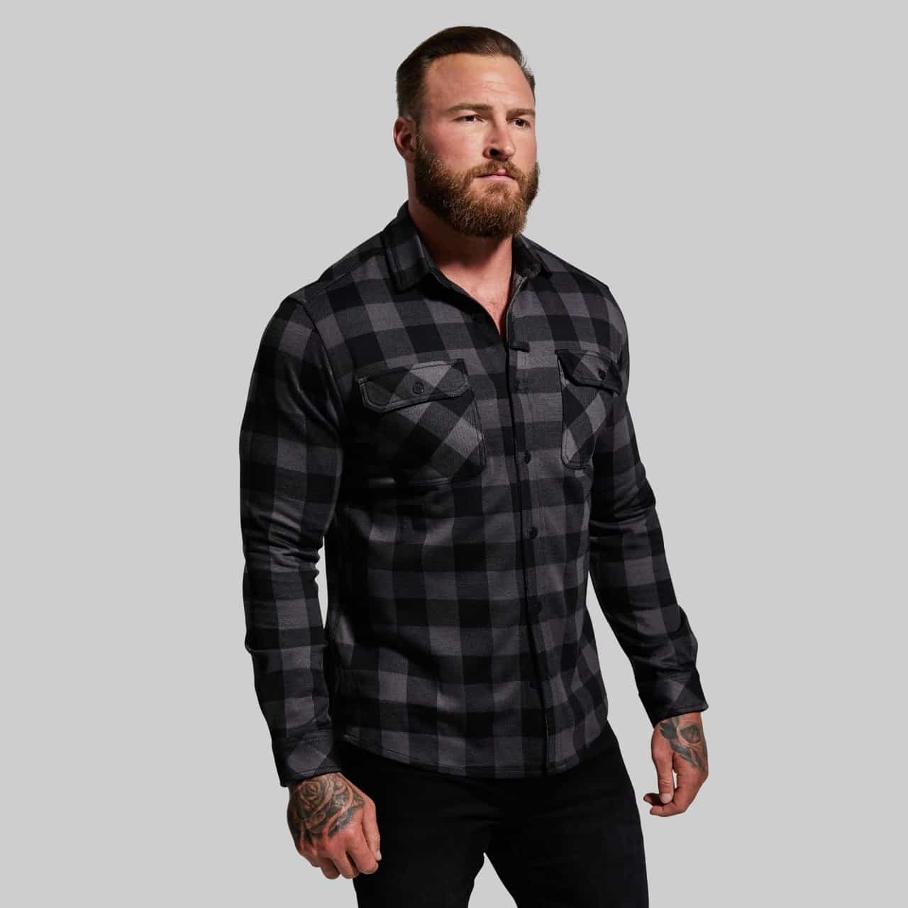 Man wearing a black and gray plaid shirt on a gray background