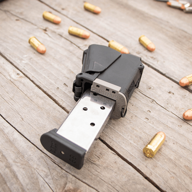 Maglula Universal Pistol Magazine Loader UpLULA Black color with handgun magazine on a wooden surface with firearms around