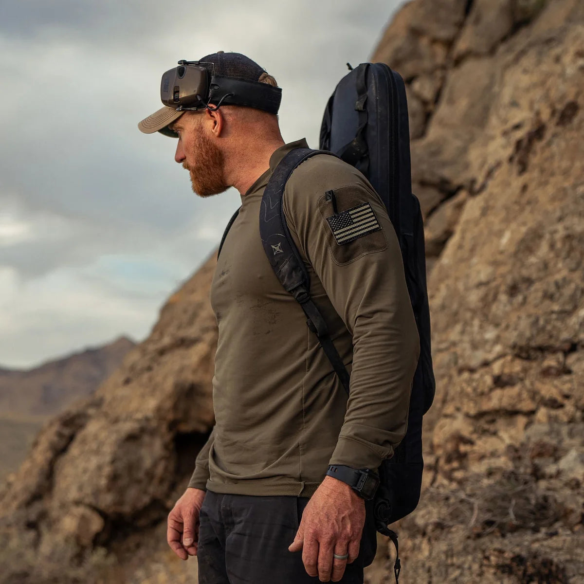Vertx Men's Enduro Training Long Sleeve Shirt in Ranger Green outdoors, side view with sleeve patch