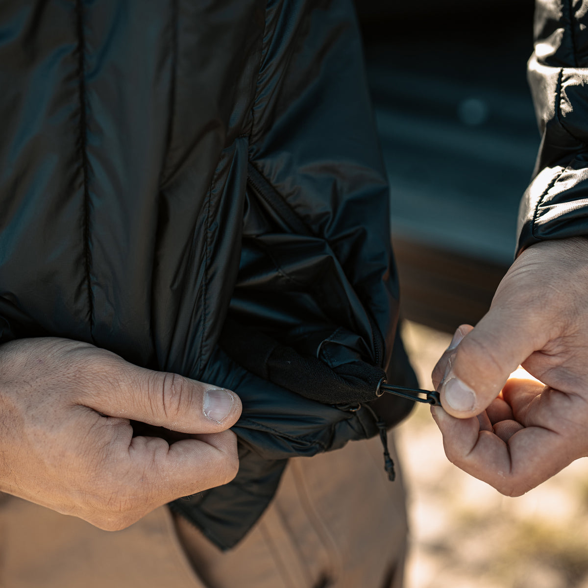 Close-up of adjustable hem drawcord on Black Vertx InBound UltraLight Puffer Jacket