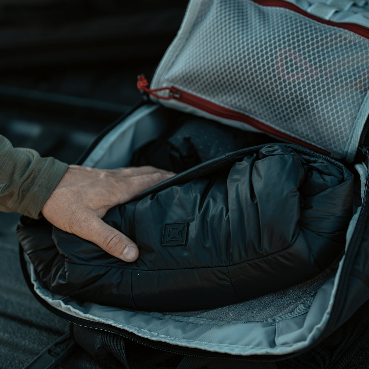 Black Vertx InBound UltraLight Puffer Jacket packed compactly in an open travel bag