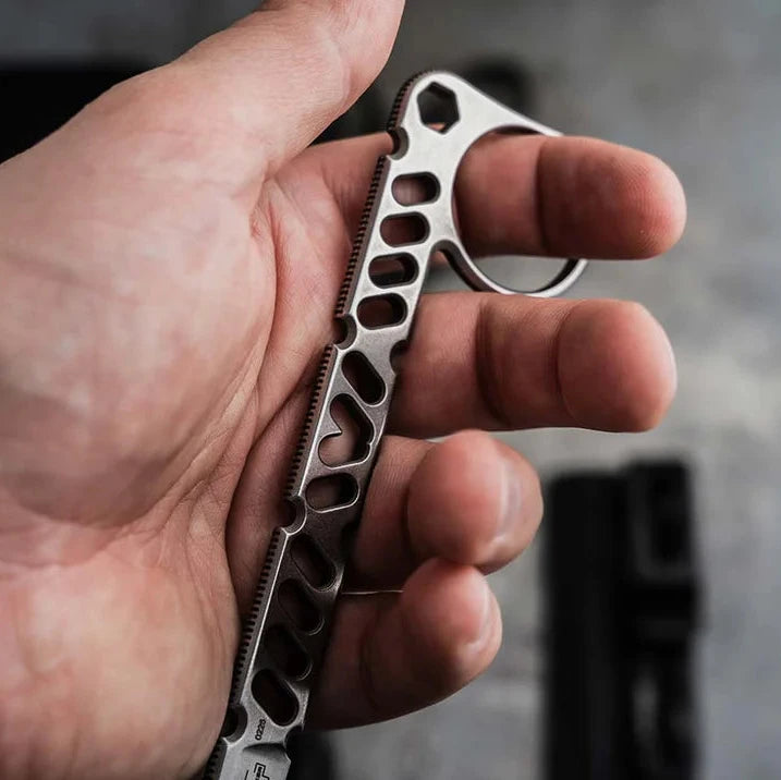 A close-up of a hand holding a Boeker Sigurd 42 with a finger loop and cutout handle, set against a blurred gray background.