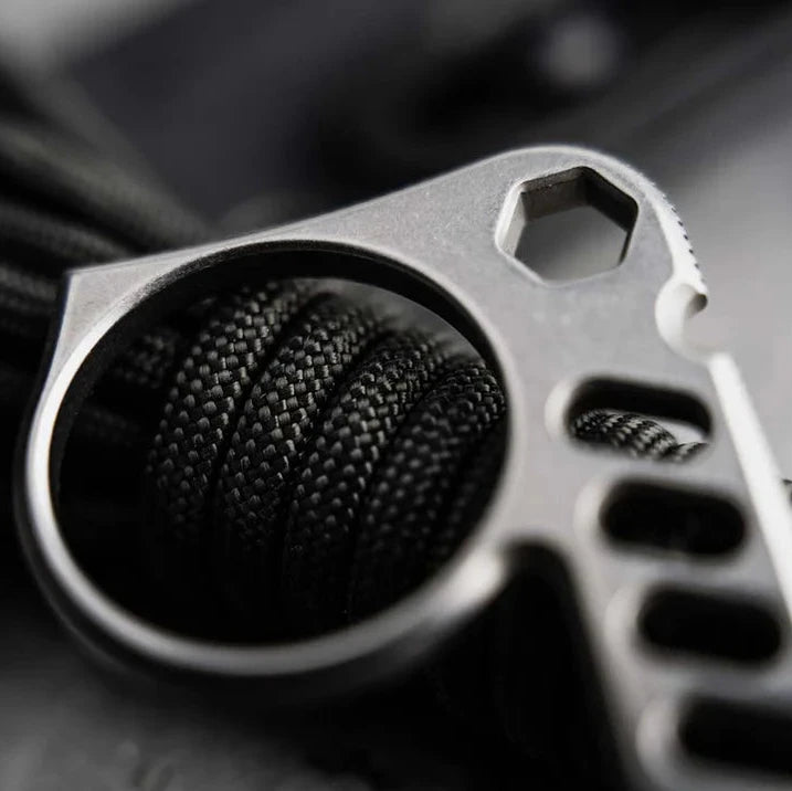 A close-up of a hand holding a Boeker Sigurd 42 with bottle opener and other tools on a textured surface