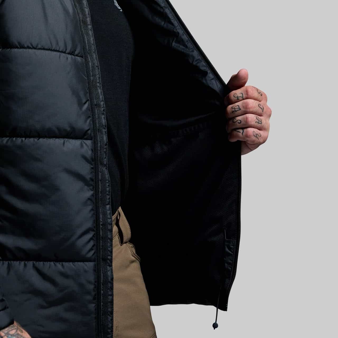 Person wearing a black puffer jacket with a gray background