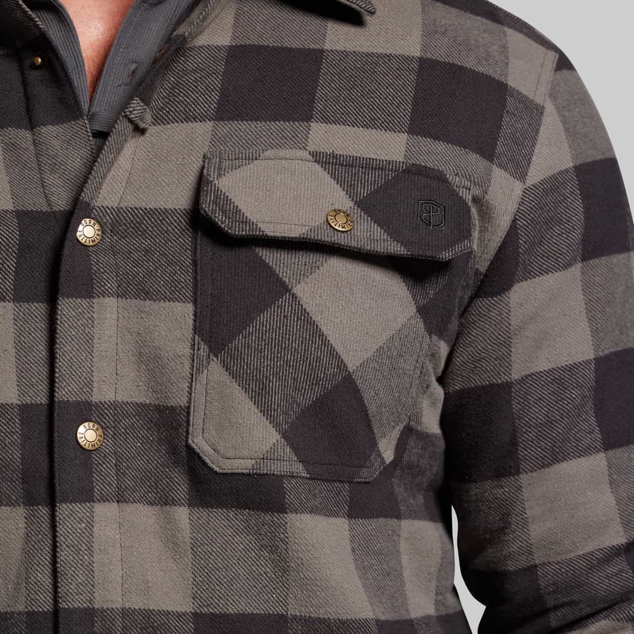 Close-up of a gray and black checkered shirt with buttons on a neutral background