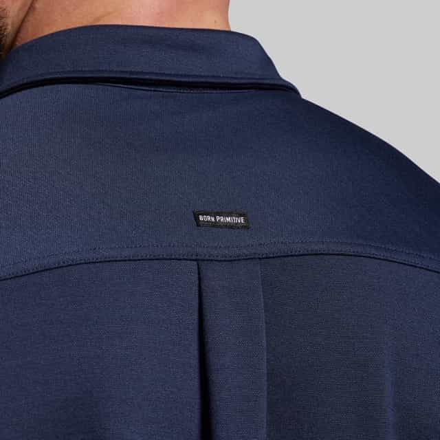 Navy blue shirt with a brand label on the collar against a gray background