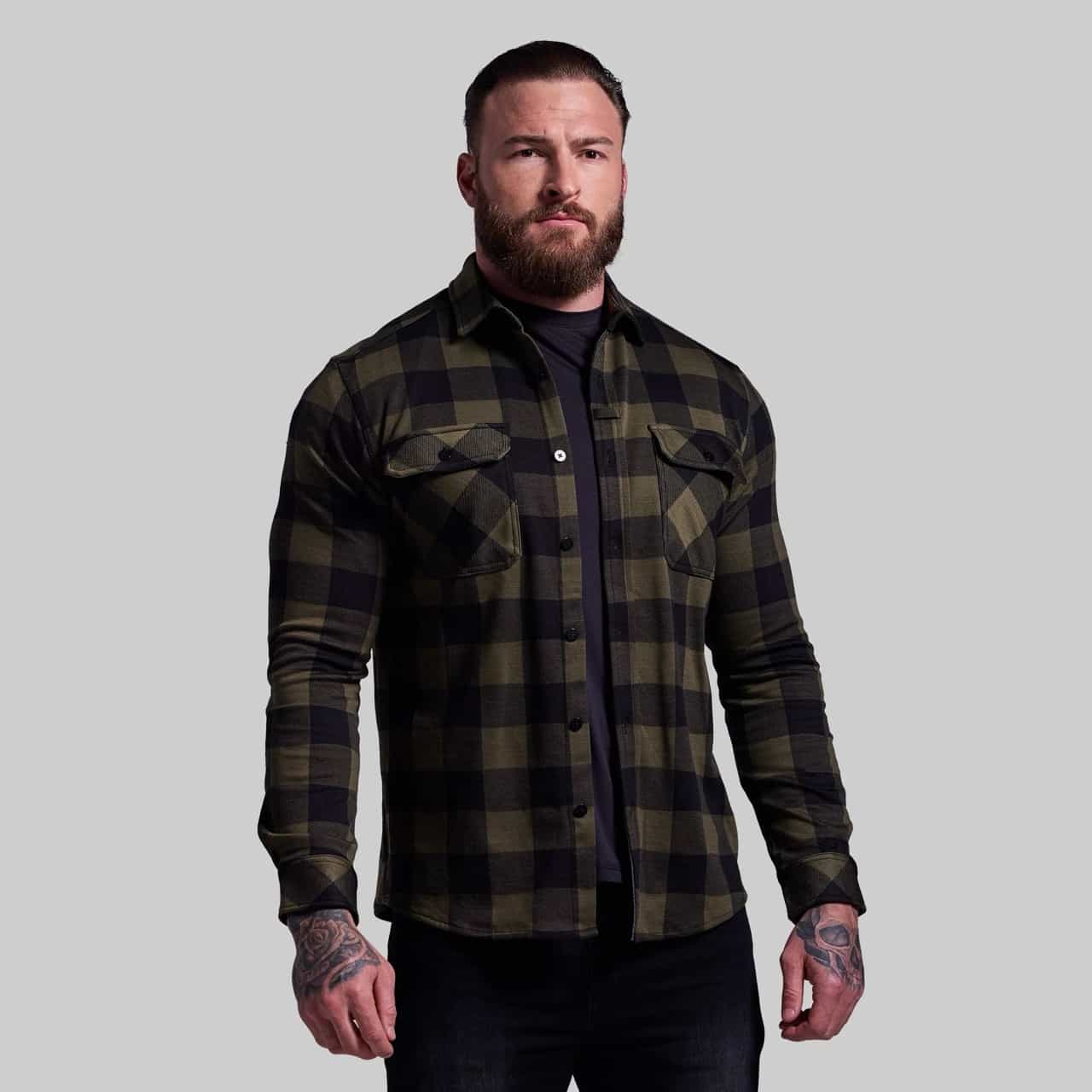 Man wearing a green and black plaid shirt on a gray background