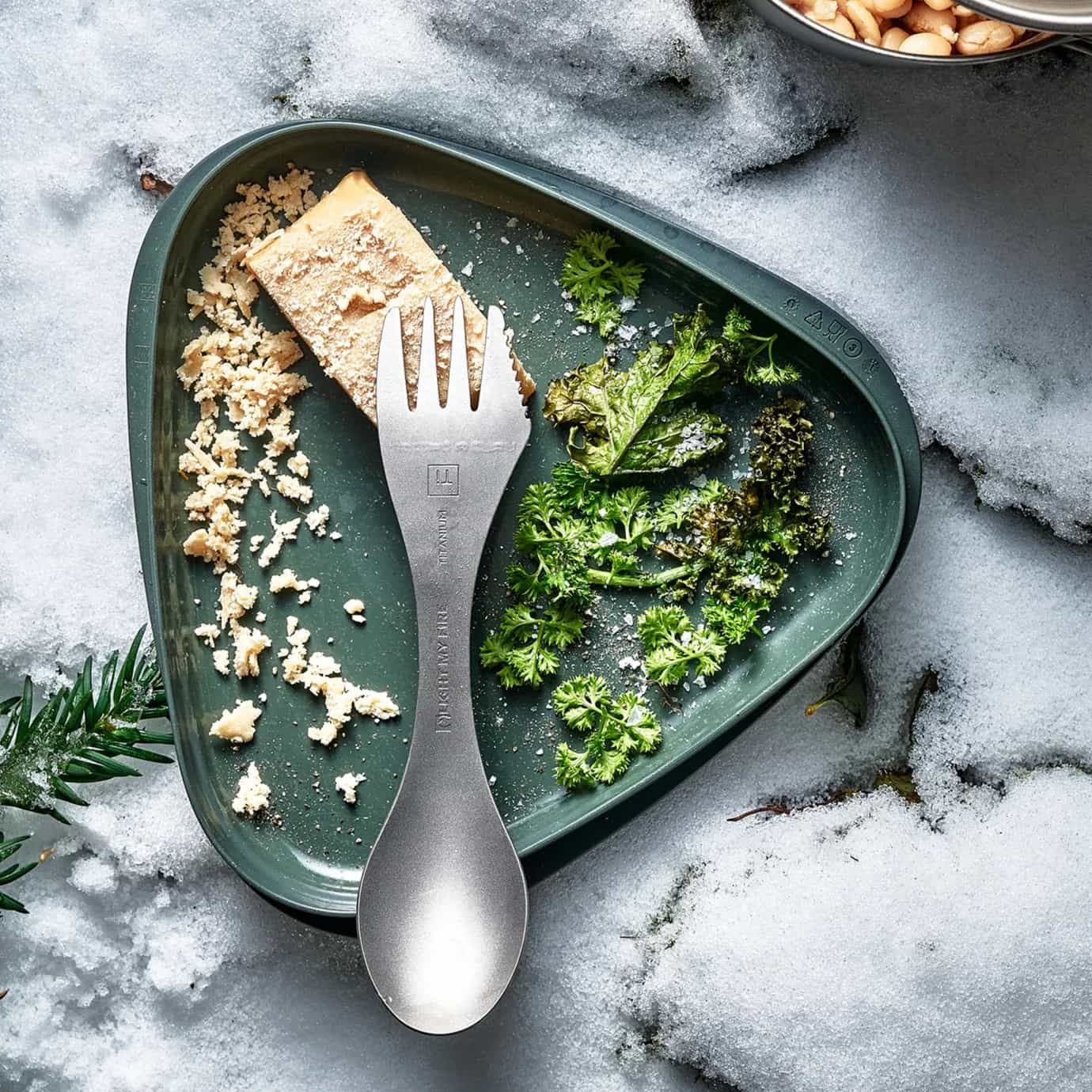 Swedish Spork Titanium and Green plate with food and utensils on a snowy surface