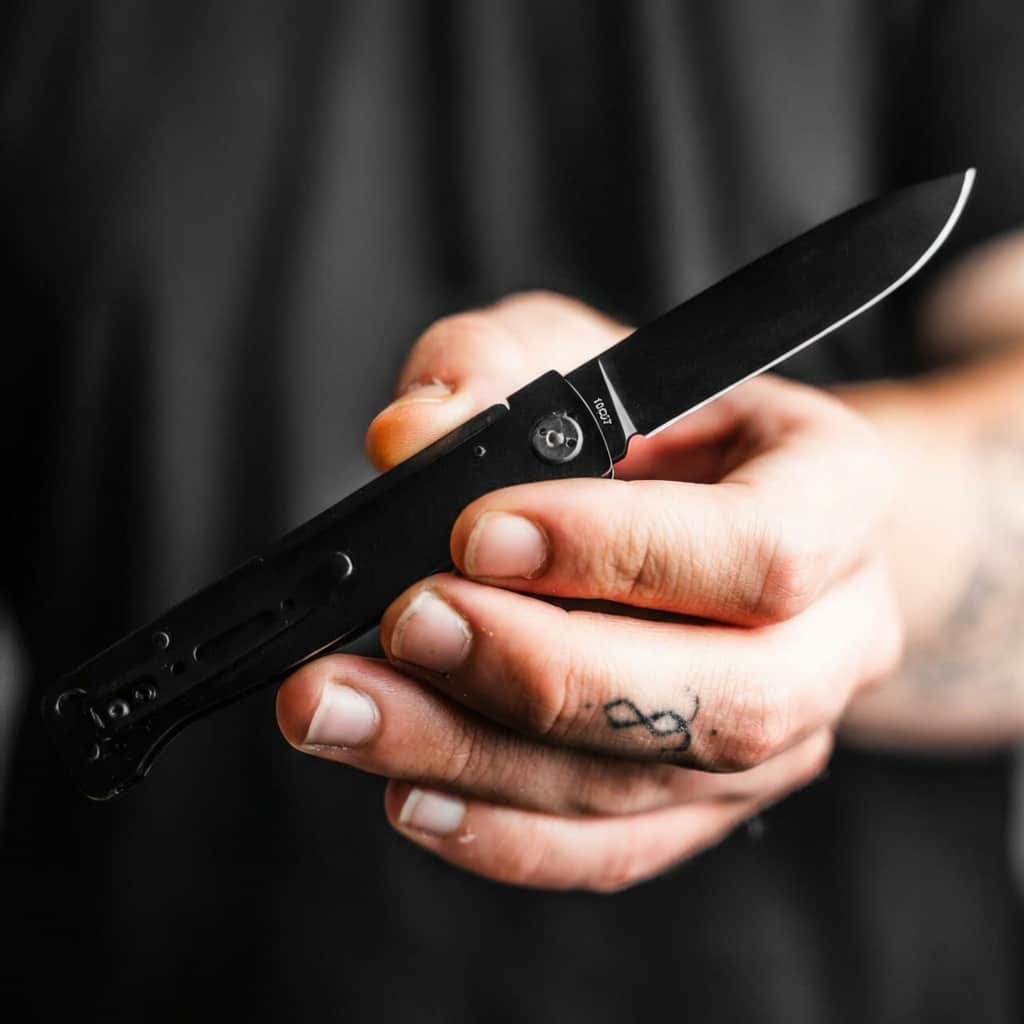 Person holding Böker Plus Atlas All Black pocket foldable knive EDC with a blurred background