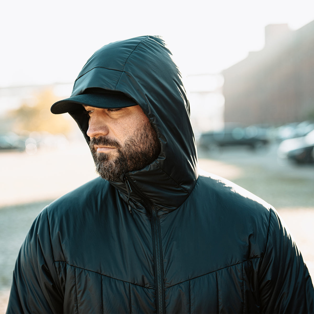 Vertx InBound UltraLight Puffer Jacket in Black with hood raised, worn outdoors